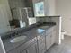 Bathroom features double sinks with granite countertop, gray cabinets, and a large mirror at 1449 Marjorie Ln, North Port, FL 34286