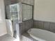 Modern bathroom featuring a soaking tub, tiled walls, and a glass-enclosed shower at 1449 Marjorie Ln, North Port, FL 34286