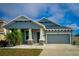Charming single-story home with a blue front door, gray garage, and well-manicured landscaping at 1280 Windy Bay Shl, Tarpon Springs, FL 34689