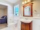 Bathroom featuring a wood vanity with decorative mirror, toilet, and view to bedroom at 2457 Tamworth Ter, Punta Gorda, FL 33983