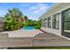 White house backyard featuring a pool, lounge and dining spaces, and lush tropical plants at 1731 Clearwater Harbor Dr, Largo, FL 33770