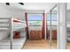 Modern bedroom with bunk beds, wood-look floors, and a mirrored closet reflecting the bright window at 1731 Clearwater Harbor Dr, Largo, FL 33770