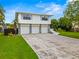 Two-story home featuring a three-car garage, stone accents, and a well-manicured lawn at 1731 Clearwater Harbor Dr, Largo, FL 33770