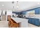Stylish kitchen with stainless appliances, white countertop island with chairs, and blue cabinets at 1731 Clearwater Harbor Dr, Largo, FL 33770