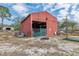 Exterior shot of red barn with roll up gate and gravel base at 8279 Sunshine Grove Rd, Brooksville, FL 34613