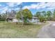 Exterior view of a one-story home featuring a concrete structure, a driveway, and green grass against a blue sky backdrop at 8279 Sunshine Grove Rd, Brooksville, FL 34613