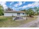 Exterior shot of a home, showcasing a concrete structure and a small yard with greenery against a bright blue sky at 8279 Sunshine Grove Rd, Brooksville, FL 34613