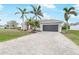 Attractive driveway leading to a modern house with a gray garage door surrounded by palm trees at 8305 Welsford Rd, Port Charlotte, FL 33981