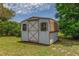 Storage shed in a yard with siding, cross beam door, and two windows at 5078 Kenmore St, Spring Hill, FL 34608