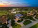 Scenic aerial view of a lavish home in a golfing community with a nearby lake as the sun sets on the horizon at 2546 Tom Morris Dr, Sarasota, FL 34240