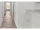 Hallway featuring light walls, wood-look flooring, and a glimpse of the kitchen countertop detail at 14183 English Sparrow Rd, Weeki Wachee, FL 34614