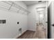 Bright laundry room with wood-look flooring, wire rack, and doorway to the hall at 14183 English Sparrow Rd, Weeki Wachee, FL 34614