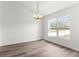 Bright, empty living room featuring a modern chandelier, hardwood flooring, and a large window at 14183 English Sparrow Rd, Weeki Wachee, FL 34614