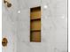 Close up of a marble tiled shower with gold fixtures and recessed shelving at 14183 English Sparrow Rd, Weeki Wachee, FL 34614