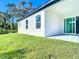 View of the backyard featuring a lush lawn, modern slider doors, and a white stucco exterior at 2576 Pecan St, North Port, FL 34287