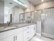 Modern bathroom with double vanity, a large mirror, and a walk-in shower with glass enclosure at 2576 Pecan St, North Port, FL 34287