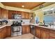 Kitchen area featuring stainless steel appliances, wooden cabinets, tile backsplash, and sink with window at 4446 Bahama Dr, Hernando Beach, FL 34607
