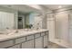 Elegant bathroom with double sinks, a marble countertop, and a walk-in shower with glass doors at 5064 Roble Ave, Spring Hill, FL 34606