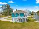View of the home's rear exterior with staircase, teal siding, white trim, and gray concrete pillars at 6771 Seaview Blvd, Hudson, FL 34667