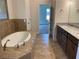 Well-appointed bathroom with a soaking tub, granite countertops, double vanity, and tile flooring for a modern aesthetic at 1220 Gantry Rd, North Port, FL 34288