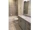 Bathroom showcasing tiled shower and tub combination with granite countertop and gray cabinets at 1608 Alliance Ave, North Port, FL 34286