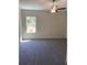 Spacious bedroom with gray carpeting, neutral walls, ceiling fan and large window with natural light at 1608 Alliance Ave, North Port, FL 34286