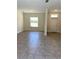 Open-concept living room with tiled floor, natural light from a large window and white trim at 1608 Alliance Ave, North Port, FL 34286