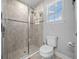Bathroom featuring a walk in shower with glass doors, toilet and a window at 17663 Turning Leaf Cir, Land O Lakes, FL 34638