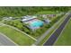 An aerial view showing the community pool with people swimming, playground and parking areas at 17663 Turning Leaf Cir, Land O Lakes, FL 34638