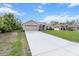 Exterior elevation showcasing a two car garage, a long driveway and grass lawn with blue skies in the background at 4196 Hoffman Ave, Spring Hill, FL 34606