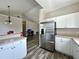 Open kitchen with stainless steel refrigerator, white cabinets, and modern flooring at 6212 Abbott Station Dr, Zephyrhills, FL 33542