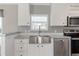Modern kitchen featuring stainless steel appliances, farmhouse sink, and white cabinetry at 13024 Dania St, Hudson, FL 34667