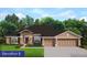 Charming single-story home with a three-car garage, manicured lawn, and beautiful landscaping at 13144 Convent Garden Rd, Brooksville, FL 34613
