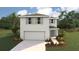 Two-story home featuring a neutral color scheme, attached garage, manicured lawn, and complementary landscaping at 30948 Silver Stage Dr, Brooksville, FL 34602
