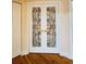Hallway showcasing decorative glass double doors with gold hardware and hardwood floors at 852 3Rd Ave S, Tierra Verde, FL 33715