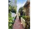 Charming brick walkway between home and fence, lined with garden beds at 852 3Rd Ave S, Tierra Verde, FL 33715