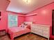 Pink bedroom featuring a plush bed, dresser, and ample natural light from the window at 6008 Angus Valley Dr, Wesley Chapel, FL 33544