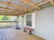 Inviting covered porch featuring wood flooring, overhead lighting, a window, and a comfortable bench at 6008 Angus Valley Dr, Wesley Chapel, FL 33544