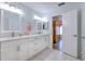 Bright bathroom with white tile, double sinks, white cabinets, and adjacent room at 7102 Silvermill Dr, Tampa, FL 33635