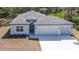 Exterior elevation of a gray home with a three car garage, manicured lawn, and fresh landscaping at 1696 Bendix Ter, North Port, FL 34286