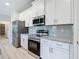 Modern kitchen featuring stainless steel appliances, white cabinetry, granite countertops and grey subway tile backsplash at 2423 Sadnet Ln, North Port, FL 34286