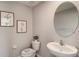 Well-lit half bathroom with a modern pedestal sink, decorative mirror, and neutral color scheme at 30835 Wild Juniper Ct, Brooksville, FL 34602