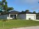A new home shows off its verdant landscaping and white exterior with a dark roof at 4097 Feather Ter, North Port, FL 34286