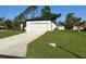 A single-story home displays a large garage, green lawn and contemporary exterior lighting at 4097 Feather Ter, North Port, FL 34286