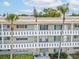 Balcony view with white seating area, exterior storm door, and tropical landscaping at 2401 Ecuadorian Way # 45, Clearwater, FL 33763