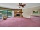 Bright living room featuring a stone fireplace, ceiling fan, and sliding doors to the outdoor patio at 1001 Old Mill Pond Rd, Palm Harbor, FL 34683