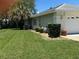 An exterior side view of the house with a well-manicured lawn, mature landscaping, and two car garage at 9685 Southern Belle Dr, Weeki Wachee, FL 34613