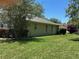 Side view of the home's exterior with a well-maintained lawn, mature landscaping, and a light-colored roof at 9685 Southern Belle Dr, Weeki Wachee, FL 34613