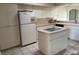 Bright eat-in kitchen featuring island with cooktop, white appliances, tile floors, and plenty of cabinet space at 9685 Southern Belle Dr, Weeki Wachee, FL 34613