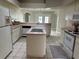 Bright eat-in kitchen featuring island with cooktop, white appliances, tile floors, and plenty of cabinet space at 9685 Southern Belle Dr, Weeki Wachee, FL 34613